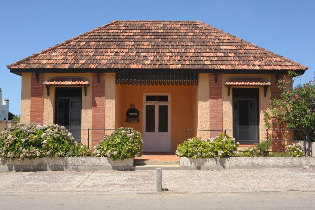 Traditional brick house with terracotta tile roof and flowering plants in La Pedrera, Uruguay.