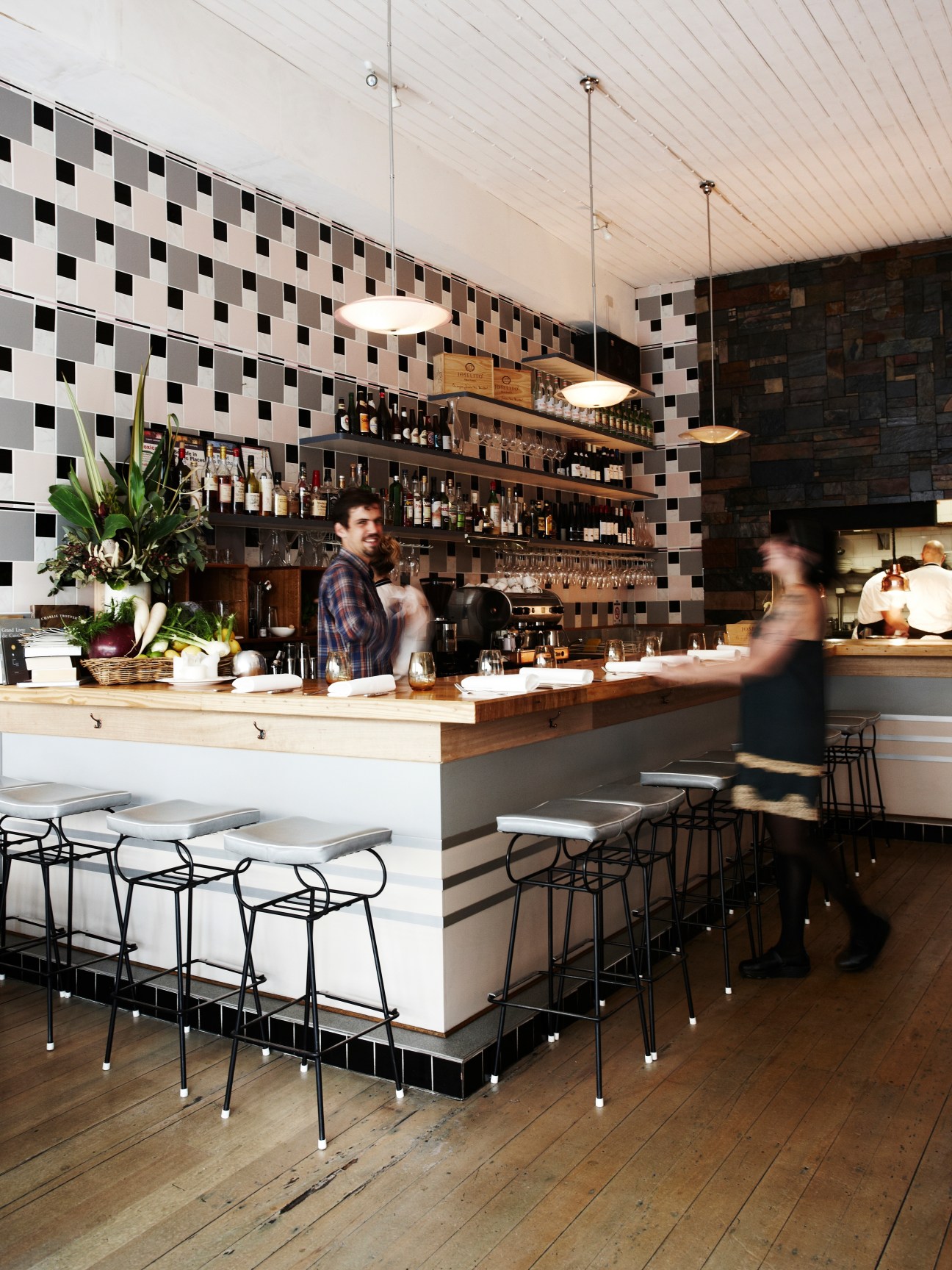 Interior of Estelle Bar & Kitchen showing a modern bar counter with geometric patterned wall and pendant lights.