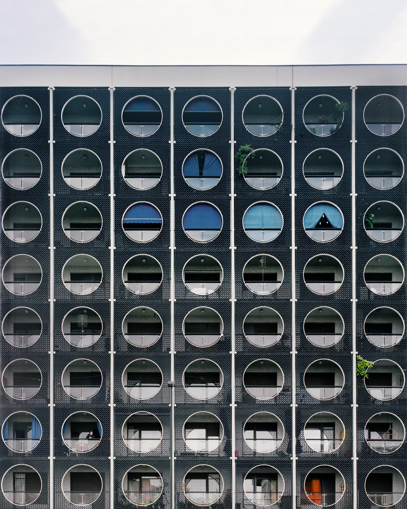 Modern apartment building with a geometric facade of circular windows arranged in a grid pattern on Corso Francia in Turin.