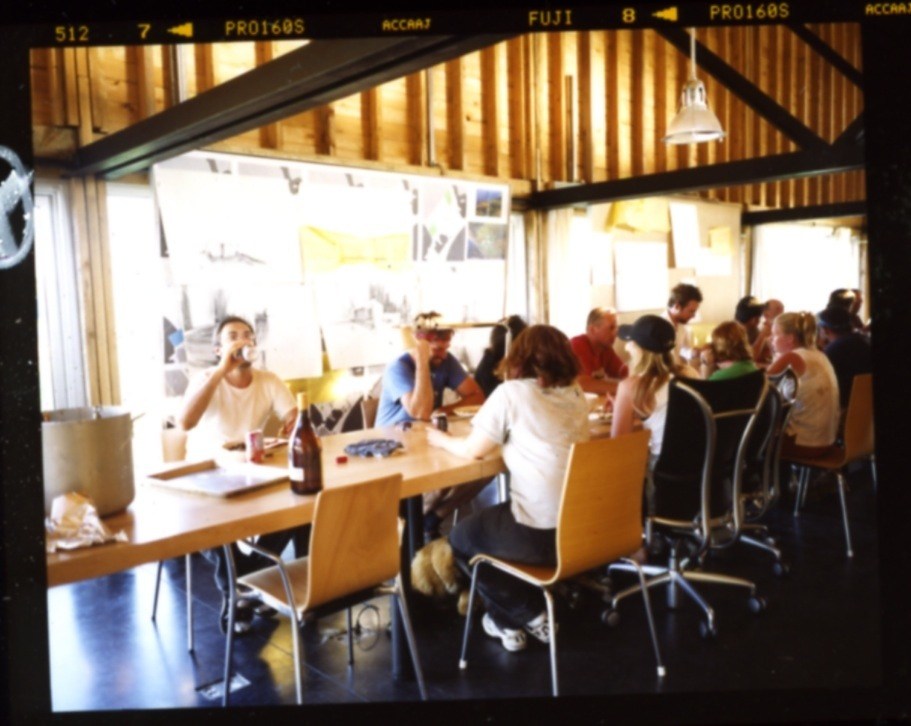 Communal table in Ghost Laboratory studio building with architects and students gathered for a meal.