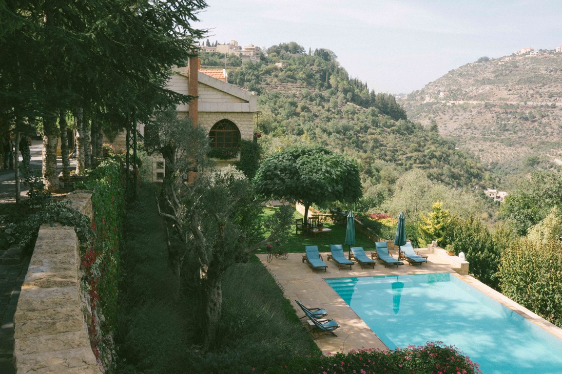 Bouyouti pool surrounded by lounge chairs and umbrellas overlooking the Chouf mountains in Lebanon.