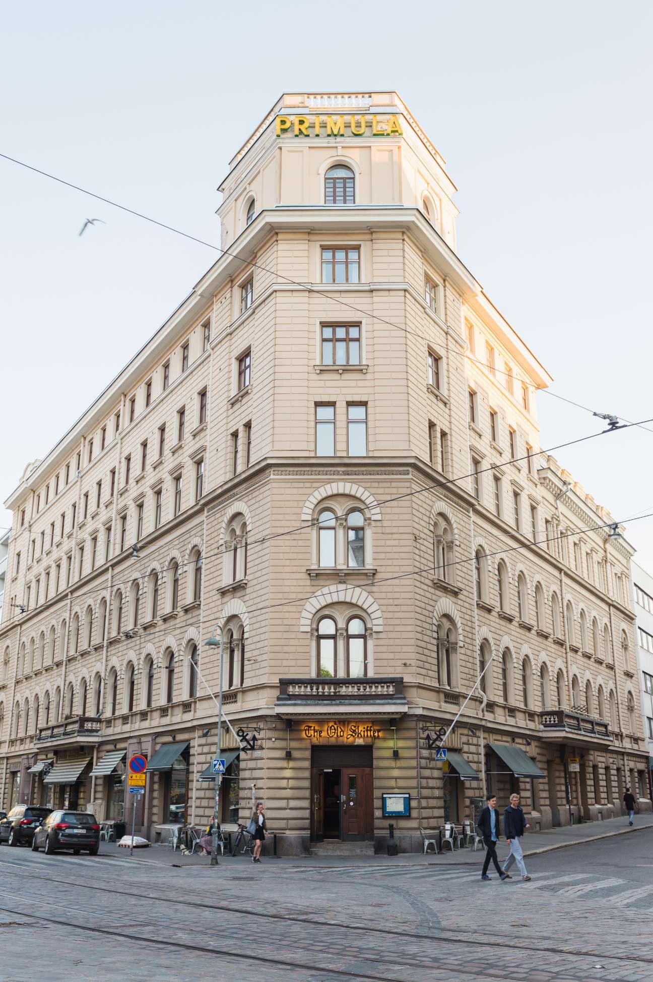 Viiskulma junction corner building with cream-colored facade and yellow Primula sign.
