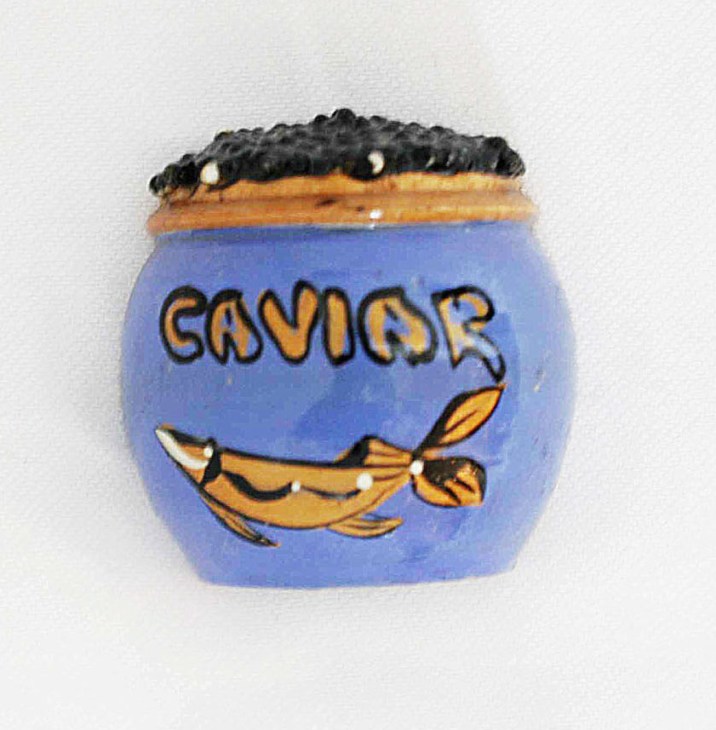 Blue ceramic fridge magnet shaped like a caviar jar with gold fish illustration and black lid.