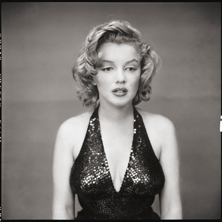 Black and white portrait photograph of a woman with wavy blonde hair wearing a sequined halter dress.