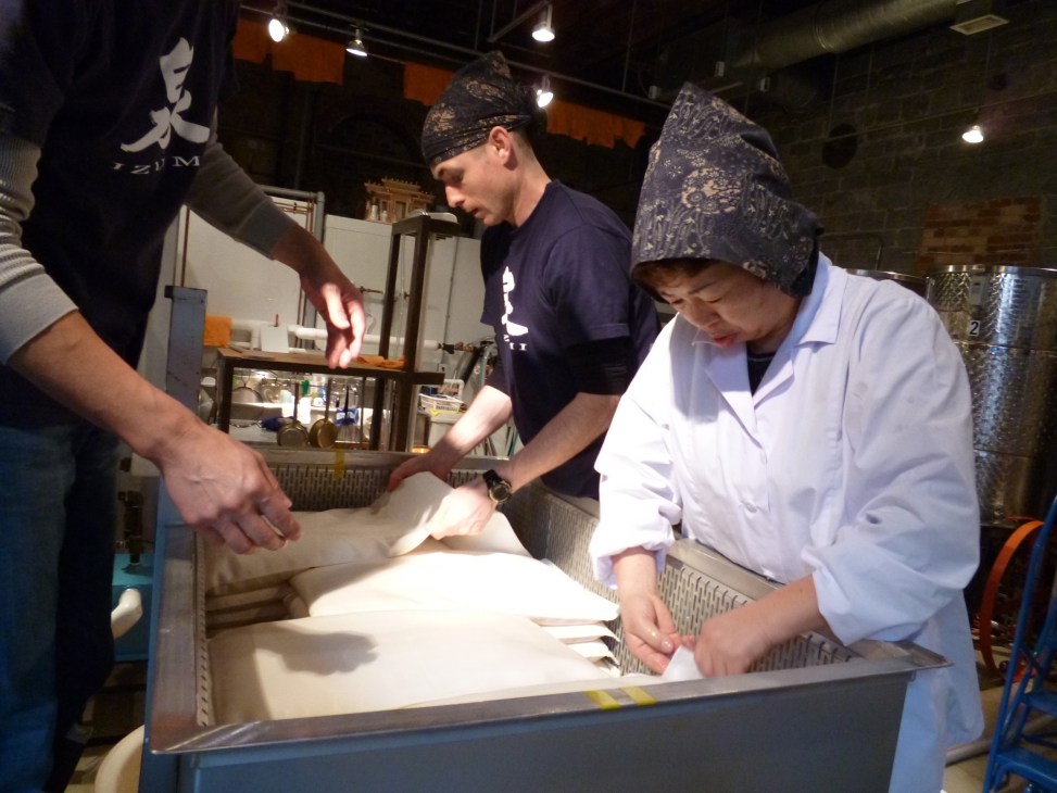 Workers at Ontario Spring Water Sake Company demonstrating sake production process at their brewing facility.
