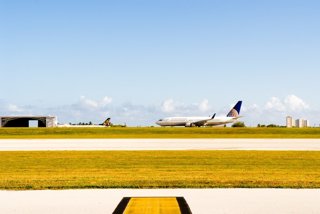 Continental Airlines Boeing 737 aircraft parked at Guam International Airport with terminal building and runway visible.