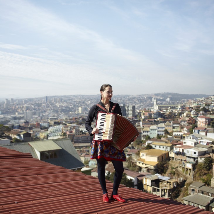 Pascuala Ilabaca, singer-songwriter, holding an accordion on a rooftop overlooking Valparaíso.