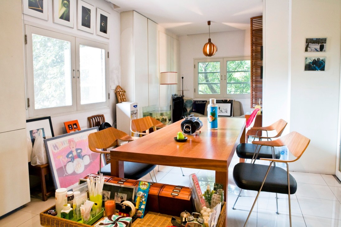 Bright modern apartment interior with wooden dining table, mid-century chairs, and artwork on walls.