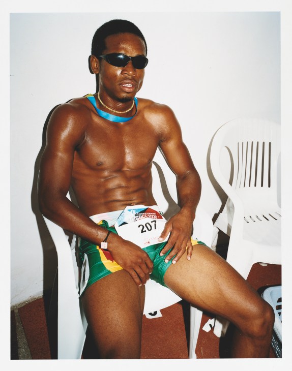 Cape Verde sprinter wearing race bib number 207 sits relaxed after completing his race.