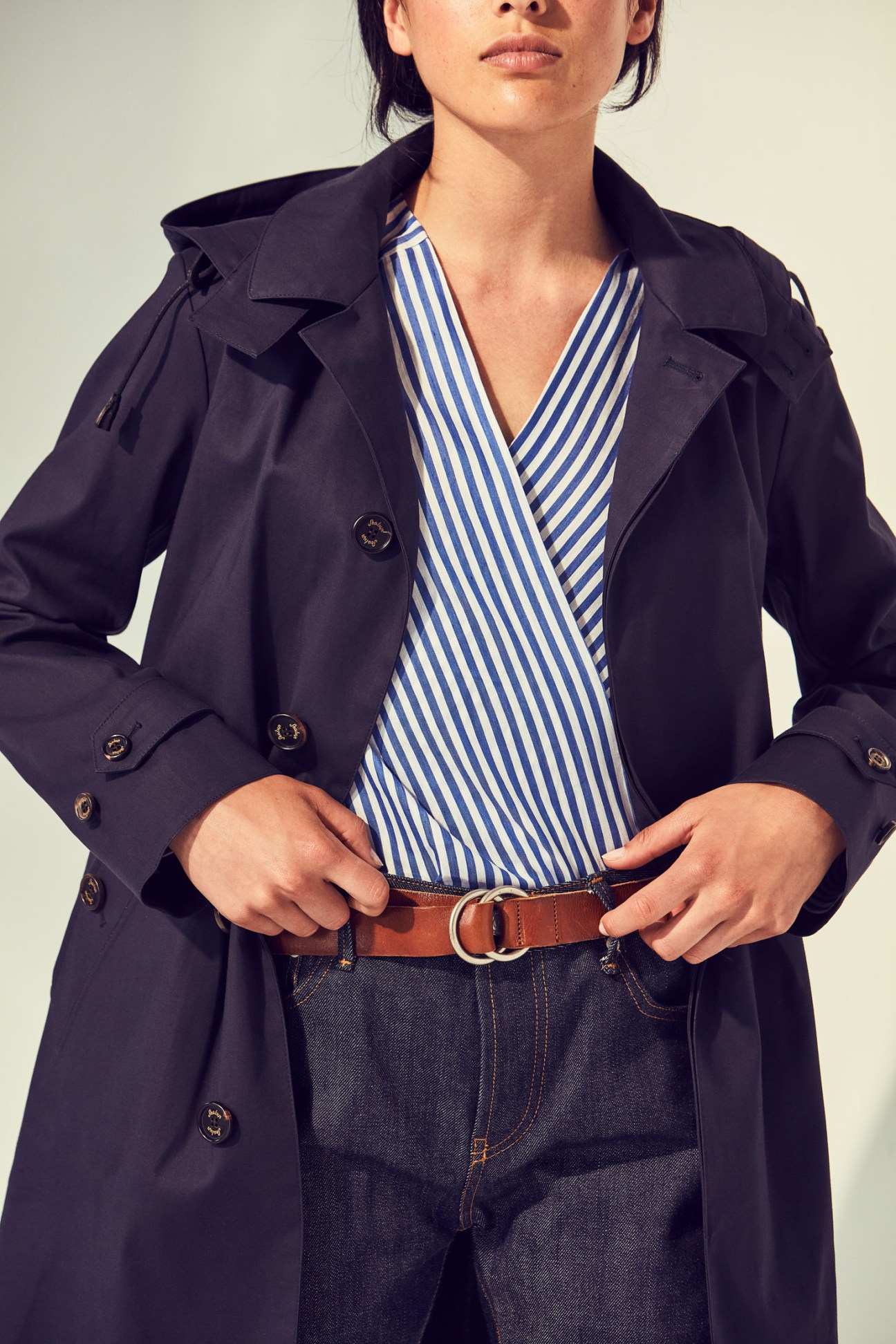 Woman wearing a navy Sealup coat, striped Roberto Collina blouse, Officine Générale jeans and Closed belt.