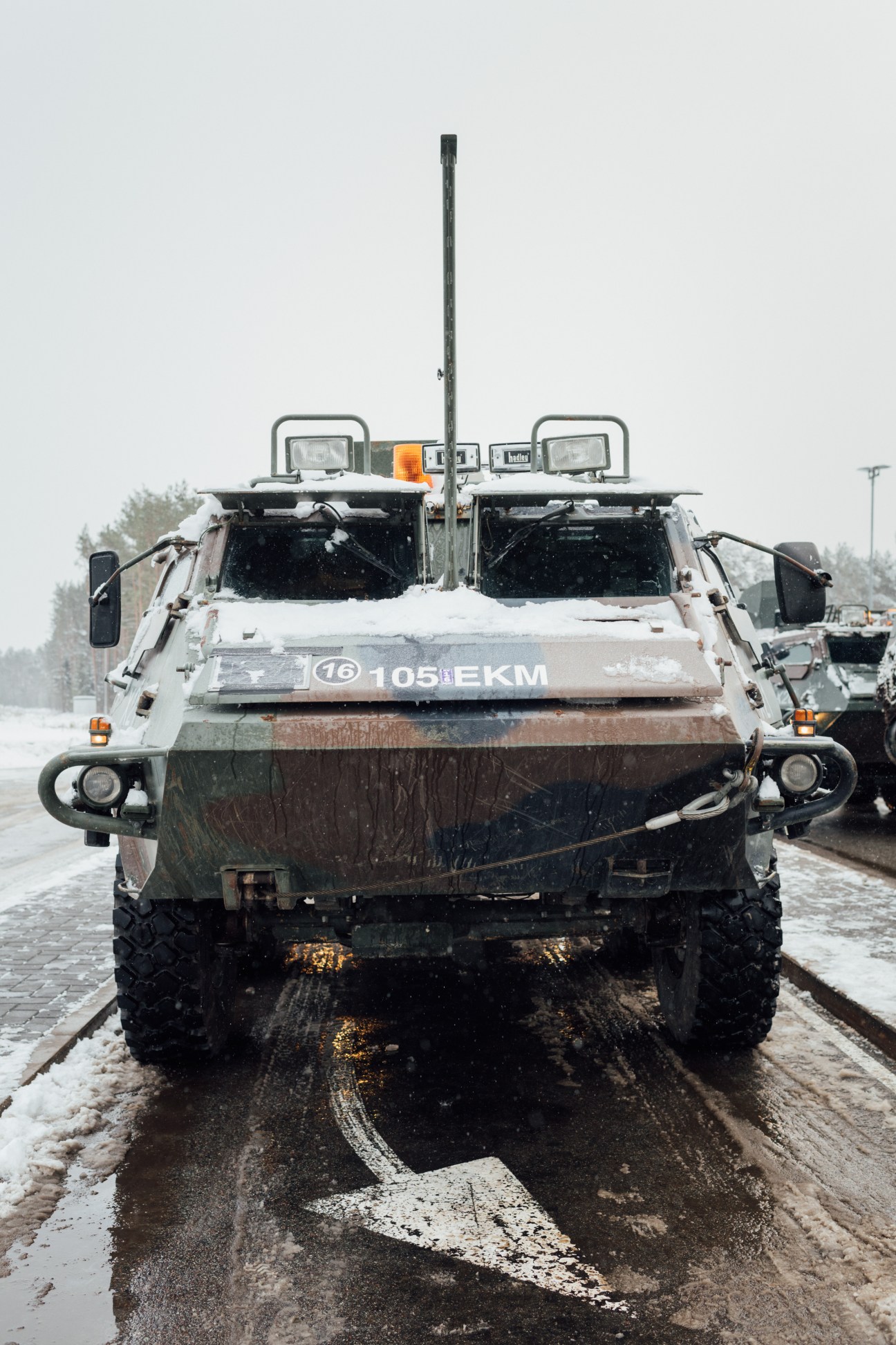 Front view of a snow-covered military truck with communications antenna parked outside Ämari airbase in Estonia.