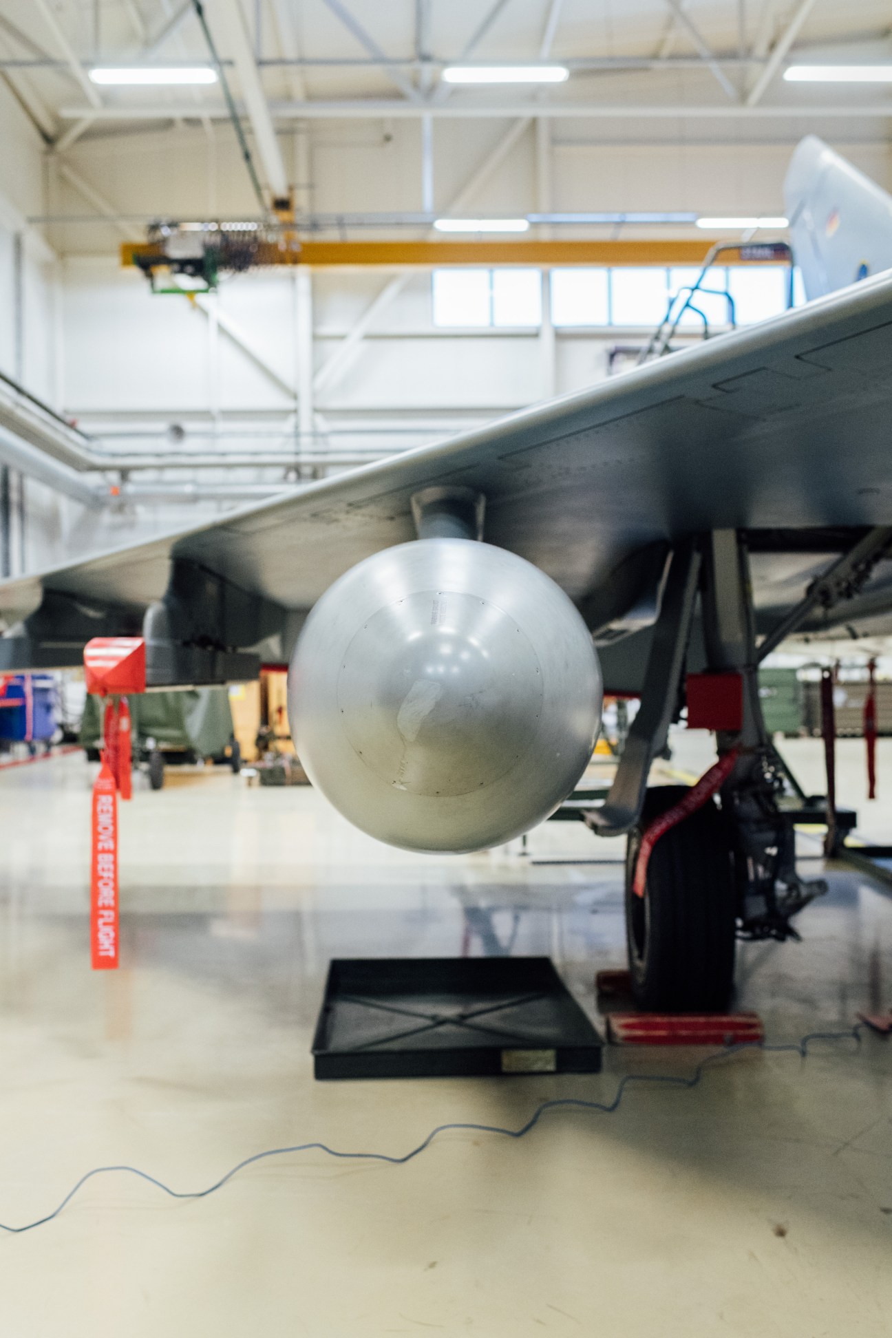 Spherical drop tank of a German fighter jet mounted in hangar with industrial ceiling