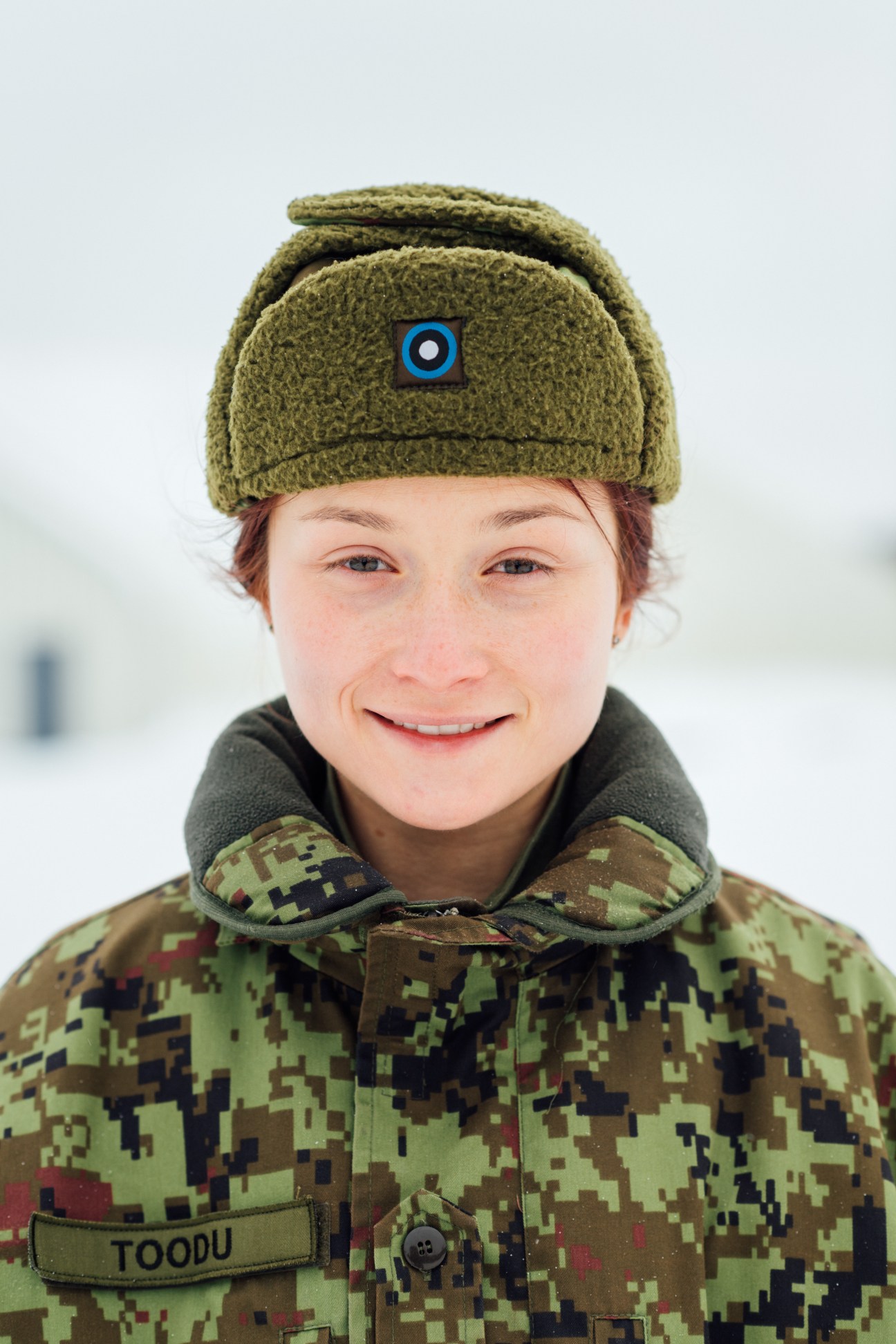 Private Laura Toodu, an Estonian soldier in digital camouflage uniform and olive wool hat, smiles at Tapa army base.