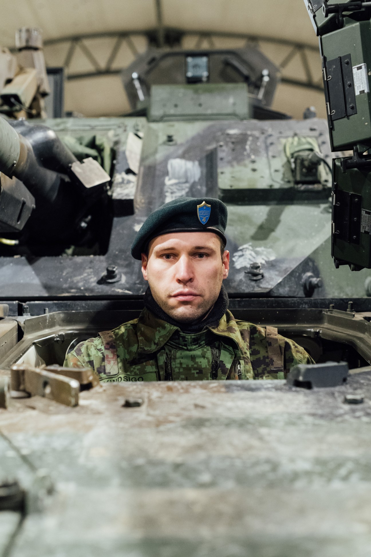 Staff Sergeant Silver Kindsigo in military camouflage uniform and blue beret sits in a combat vehicle.