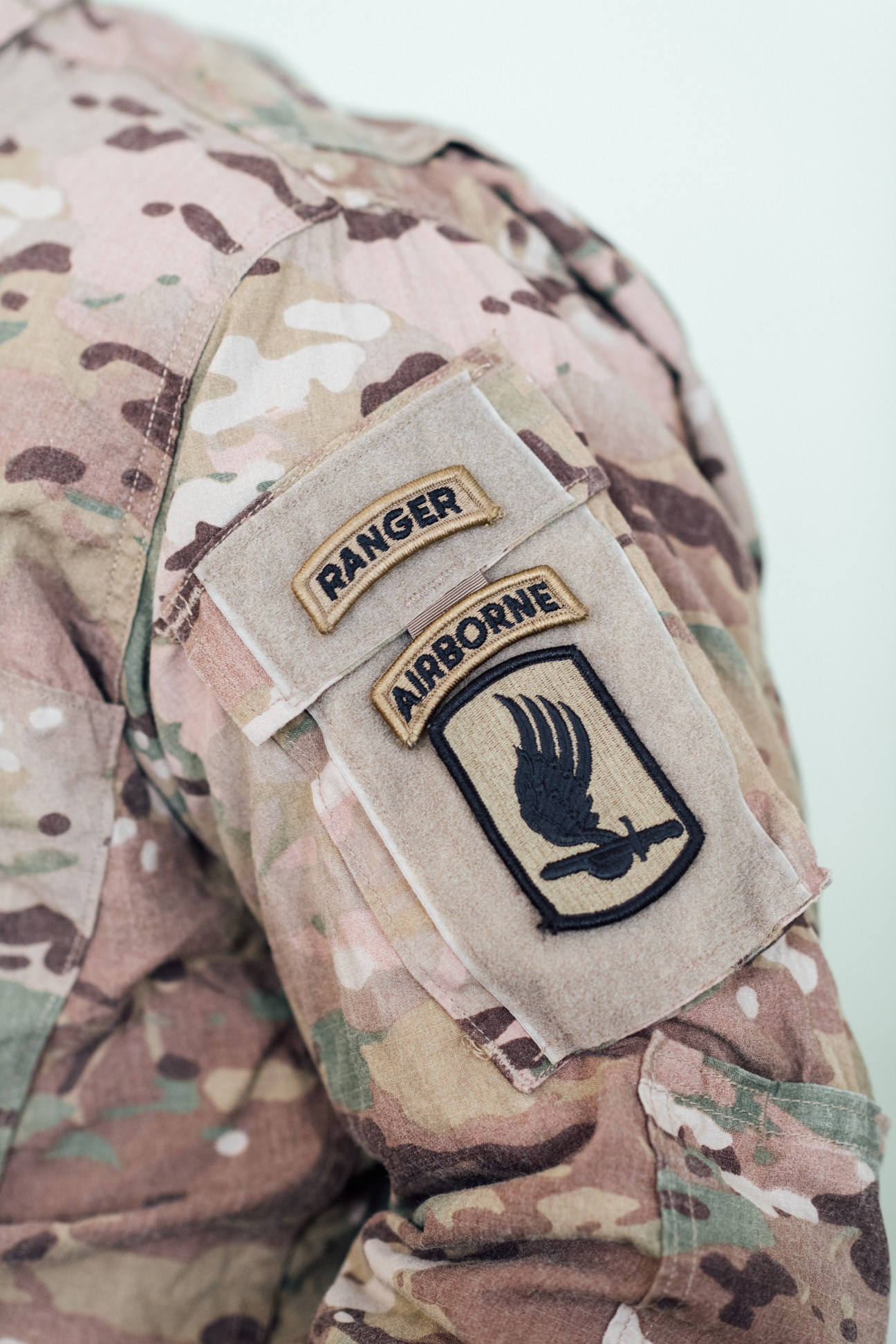 Close-up of US Army Ranger and Airborne patches on camouflage uniform sleeve.