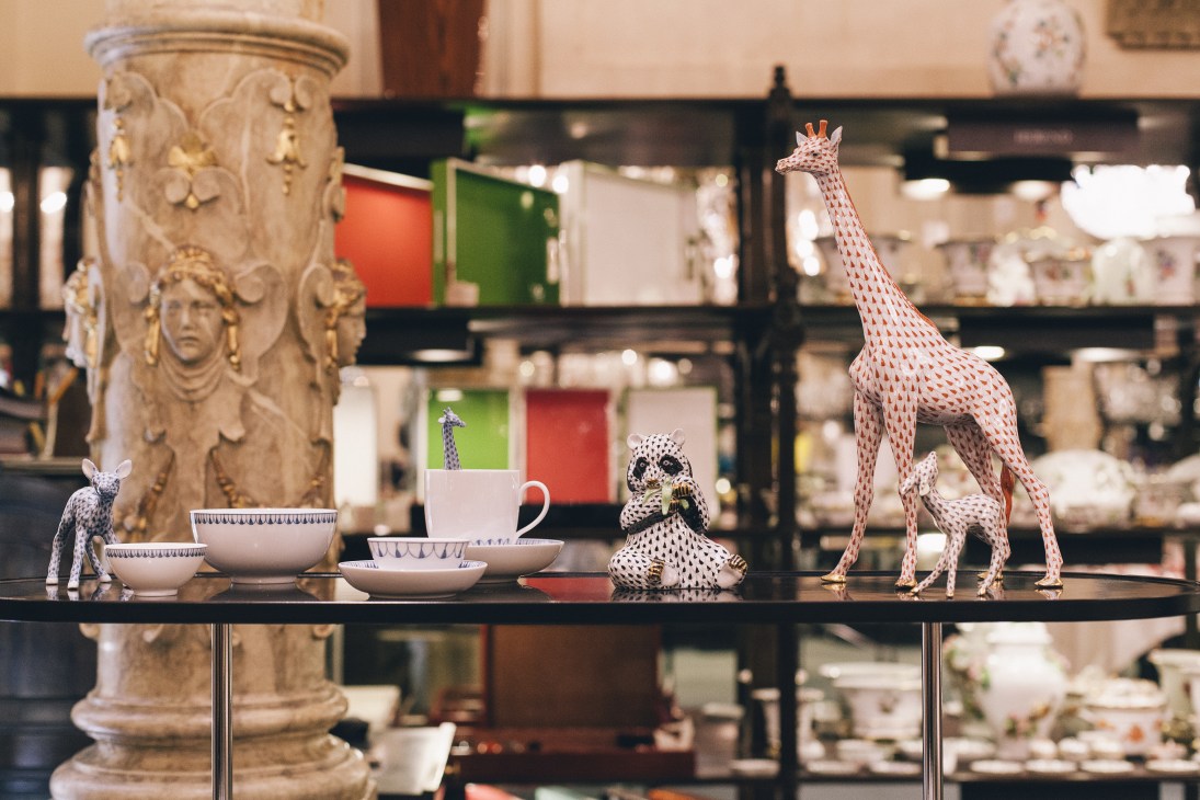 Porcelain figurines and tableware displayed on a black shelf in J&L Lobmeyr's Vienna glassware shop.