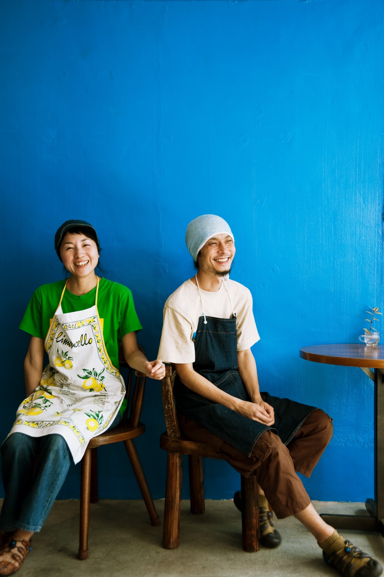 Nobuhiro and Yuko Kuwabara from Café Niceness sit smiling against a bright blue wall.