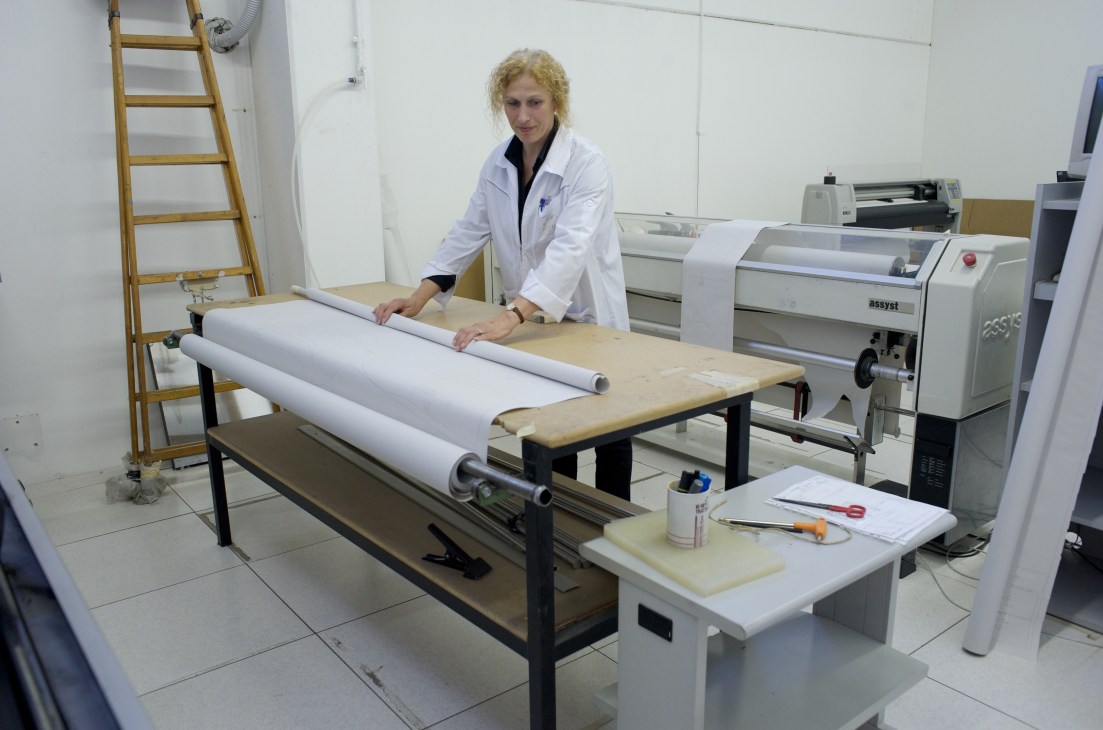 Woman in white lab coat plotting patterns on large format fabric at Cionti manufacturing facility.