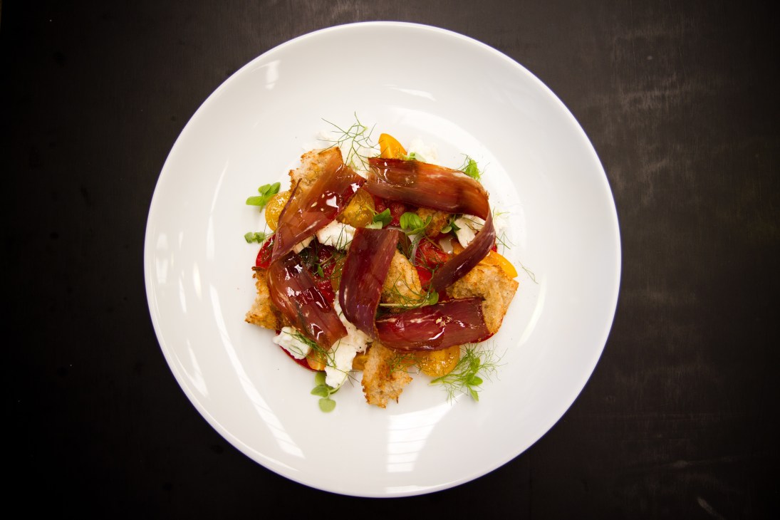 Plated dish at Hobba featuring crispy potato base with candied beets, herbs and garnishes on white plate.