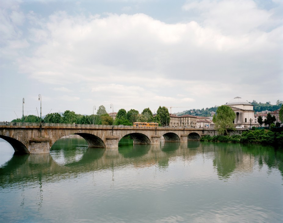 Vittorio Emanuele bridge spanning the River Po with Turin's architecture and hills visible beyond.
