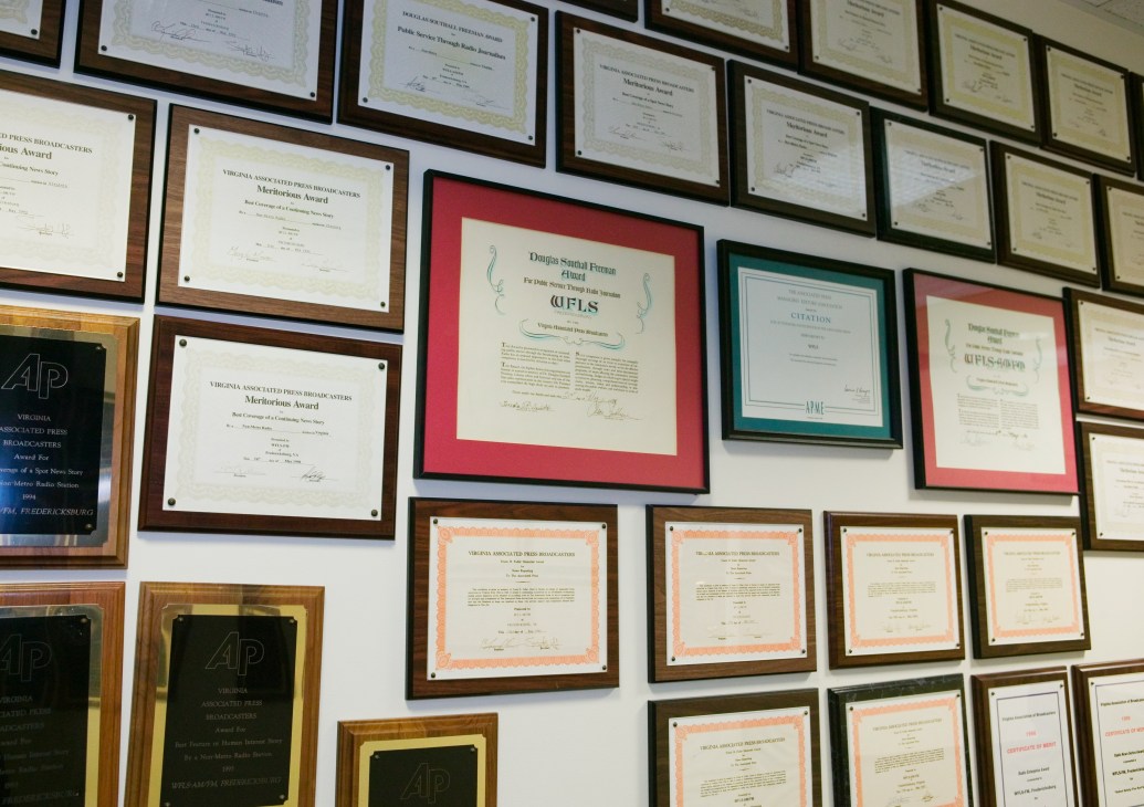 Wall display of framed awards and citations for the Free Lance-Star newspaper in various colored mats and wooden frames.