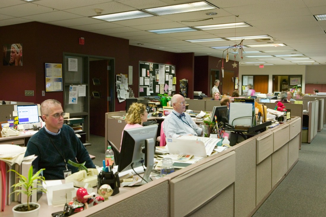 Free Lance-Star newsroom with staff members working at cubicles with computers and papers.