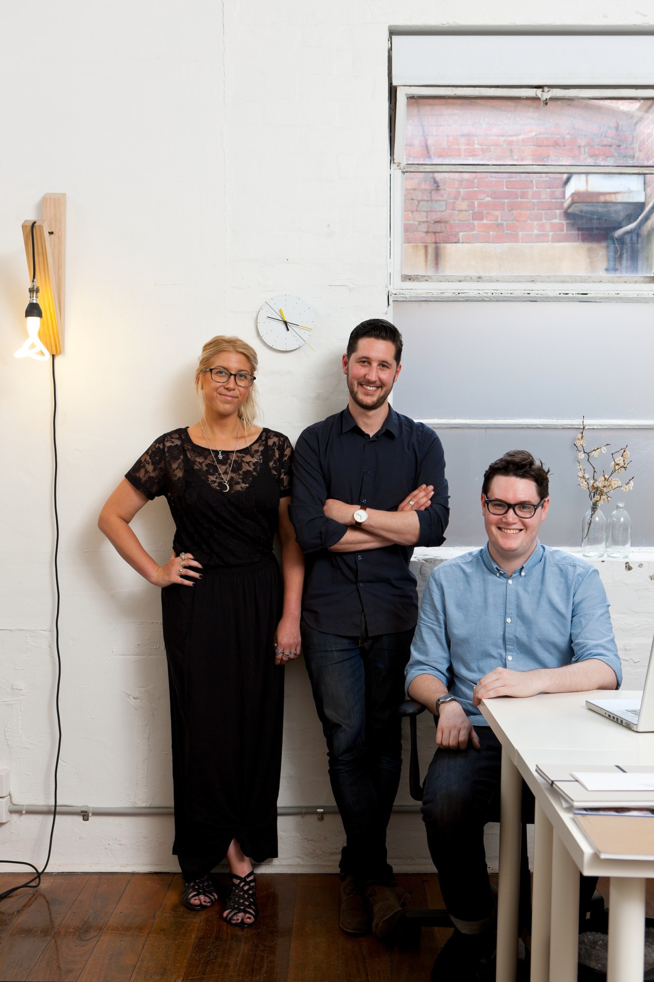 ThoughtAssembly founder Nicholas Cary poses with two team members in a modern studio office space.