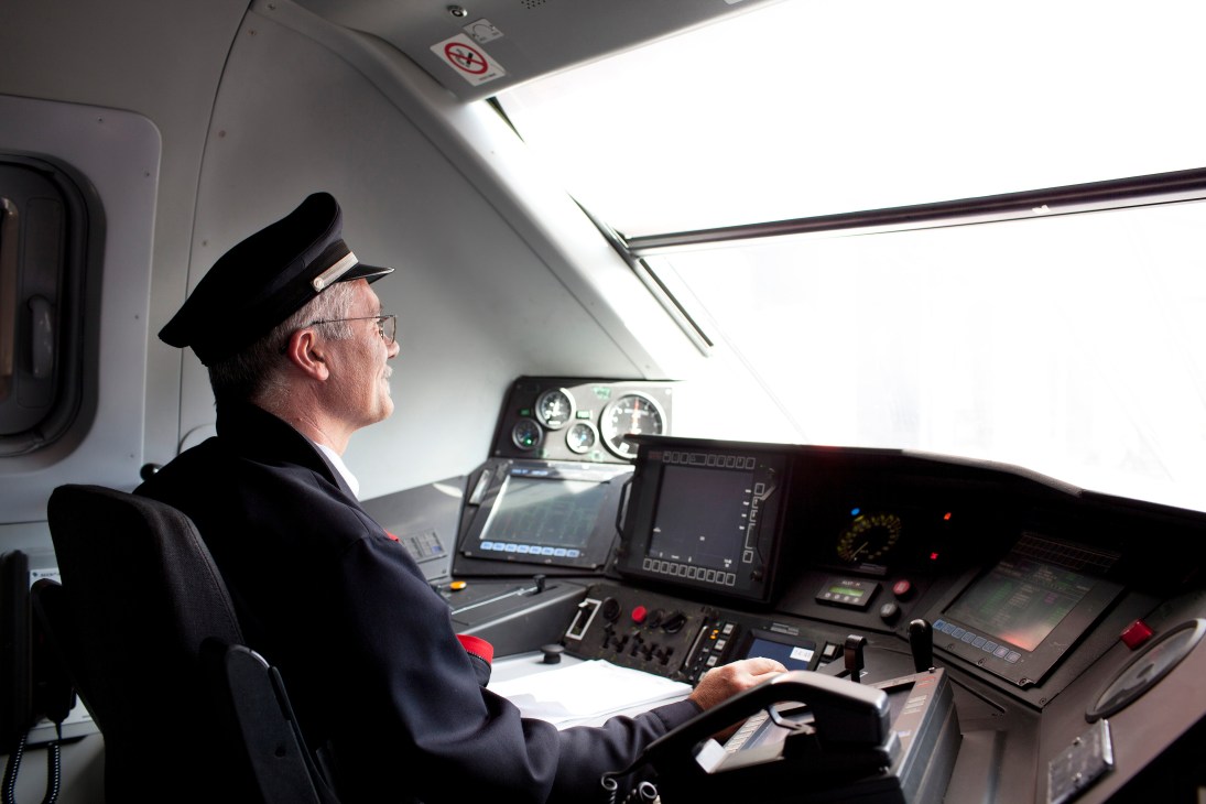 Captain in uniform at controls of Bombardier Dash-8 Q400 aircraft cockpit.