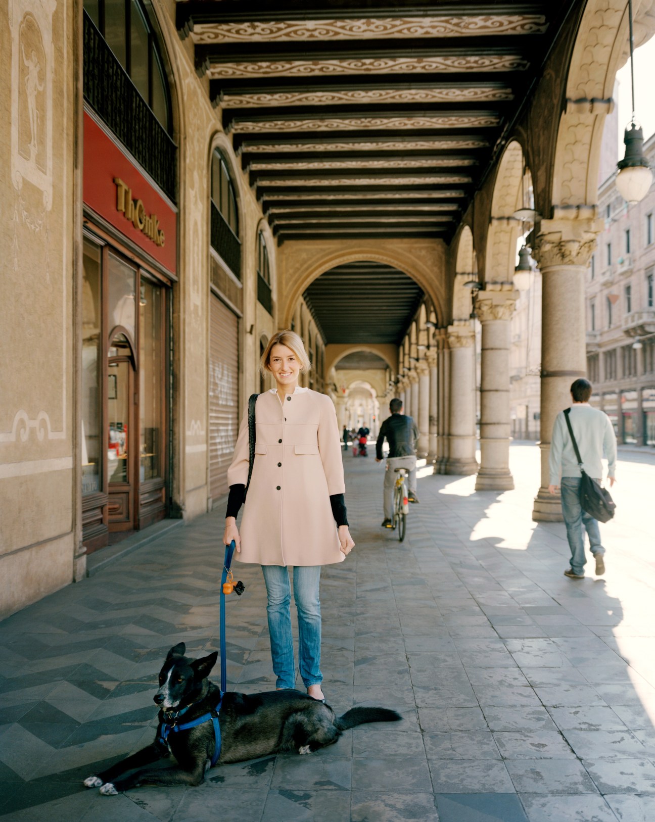 Woman with dog walking under arcade on Turin street