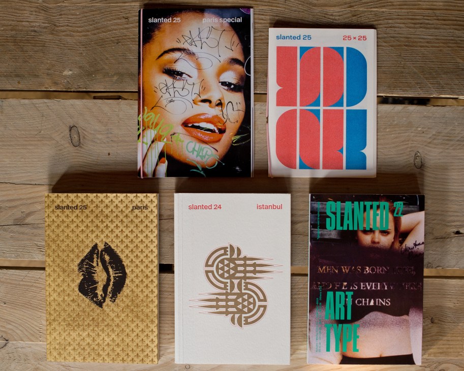 Five issues of Slanted magazine displayed on a wooden surface, showcasing diverse typography and design covers.