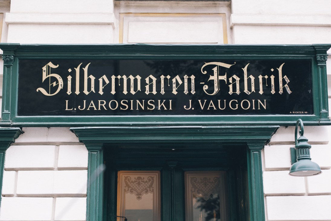 Storefront of Silberwaren Fabrik with green trim displaying Jarosinski & Vaugoin silverware shop