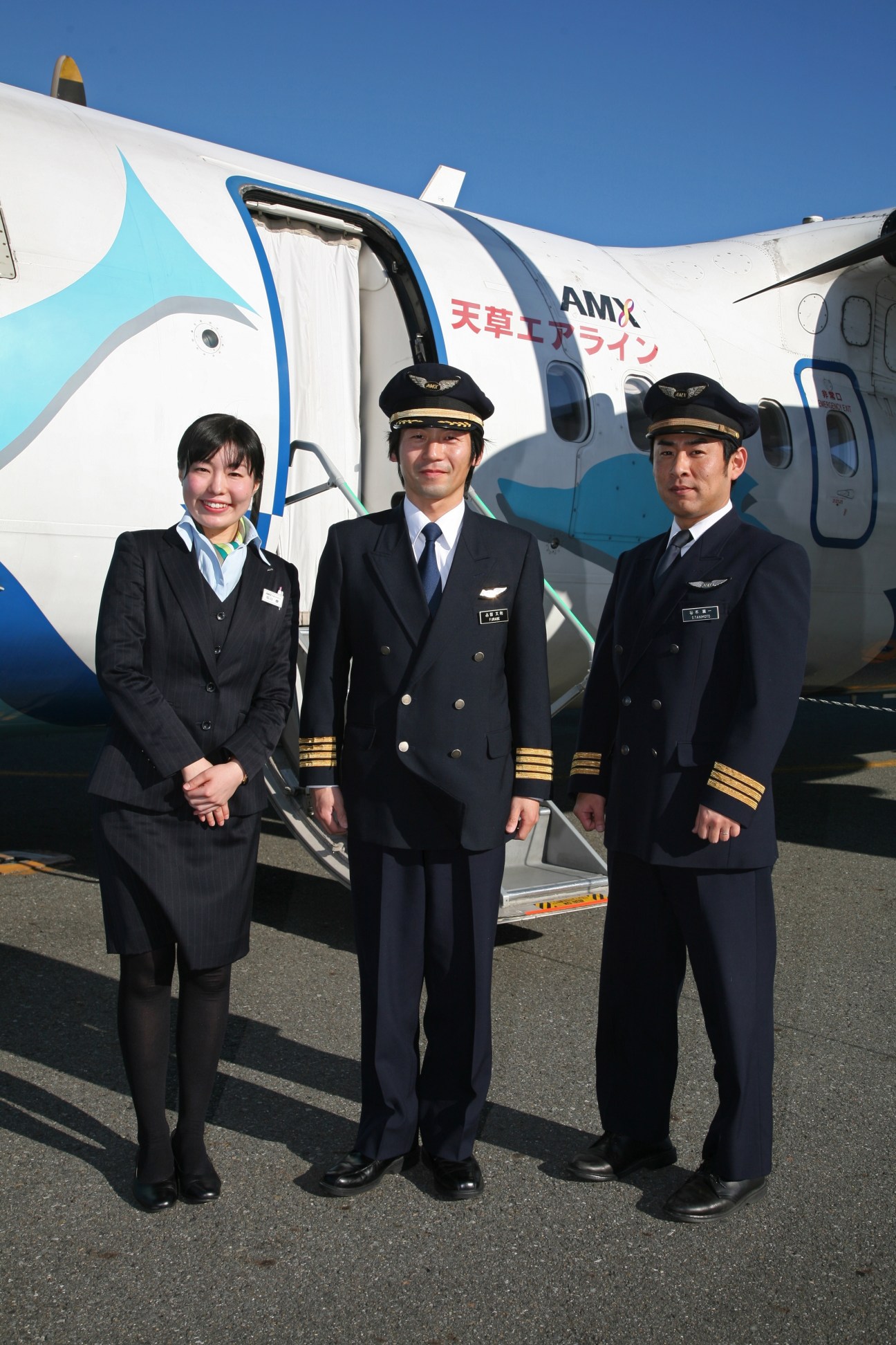 Amakusa Airlines crew standing in front of white aircraft with dolphin livery and blue trim.