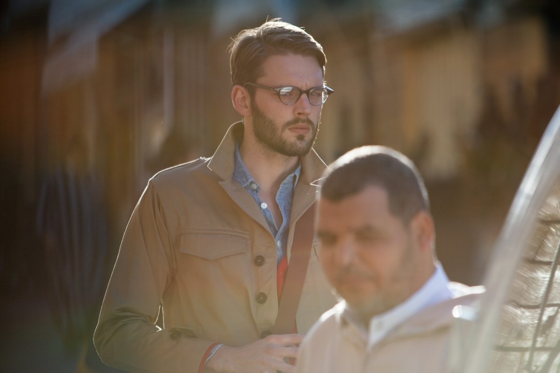 Man wearing Oliver Peoples glasses and A.P.C. jacket in Tangier's medina with blurred background.