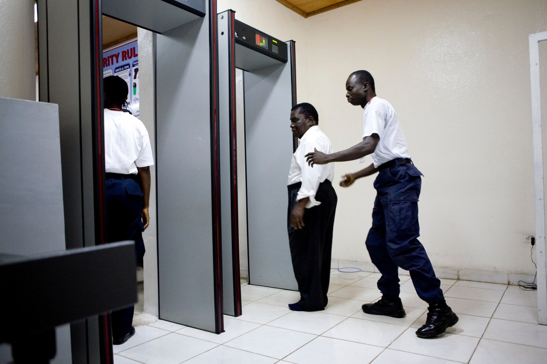 Airport security staff demonstrate passenger screening procedures at a metal detector