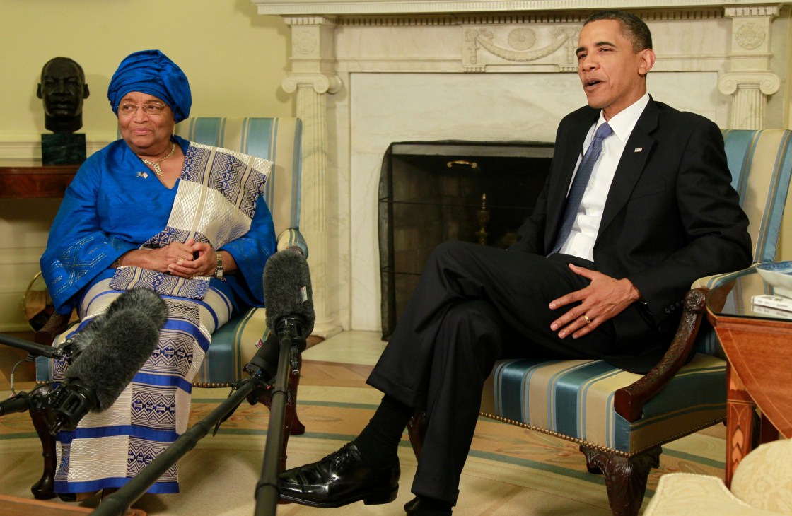 Ellen Johnson Sirleaf, president of Liberia, sits in conversation with a man in a formal setting.