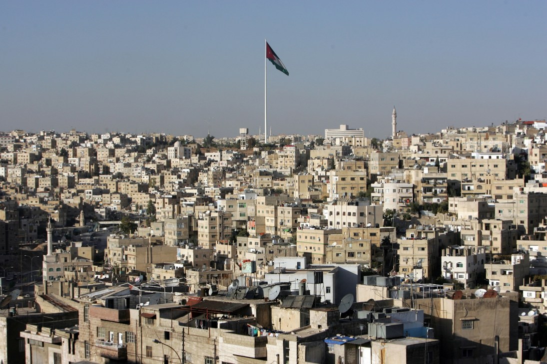 Aerial view of Amman, Jordan's capital city with densely packed buildings and a flag on a tall pole