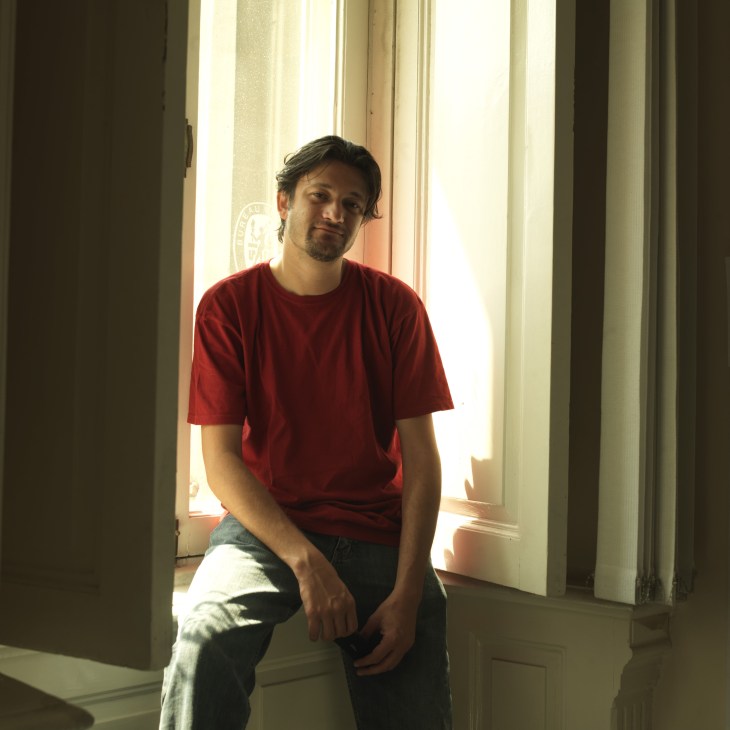 Man in red shirt sitting by window in bright natural light