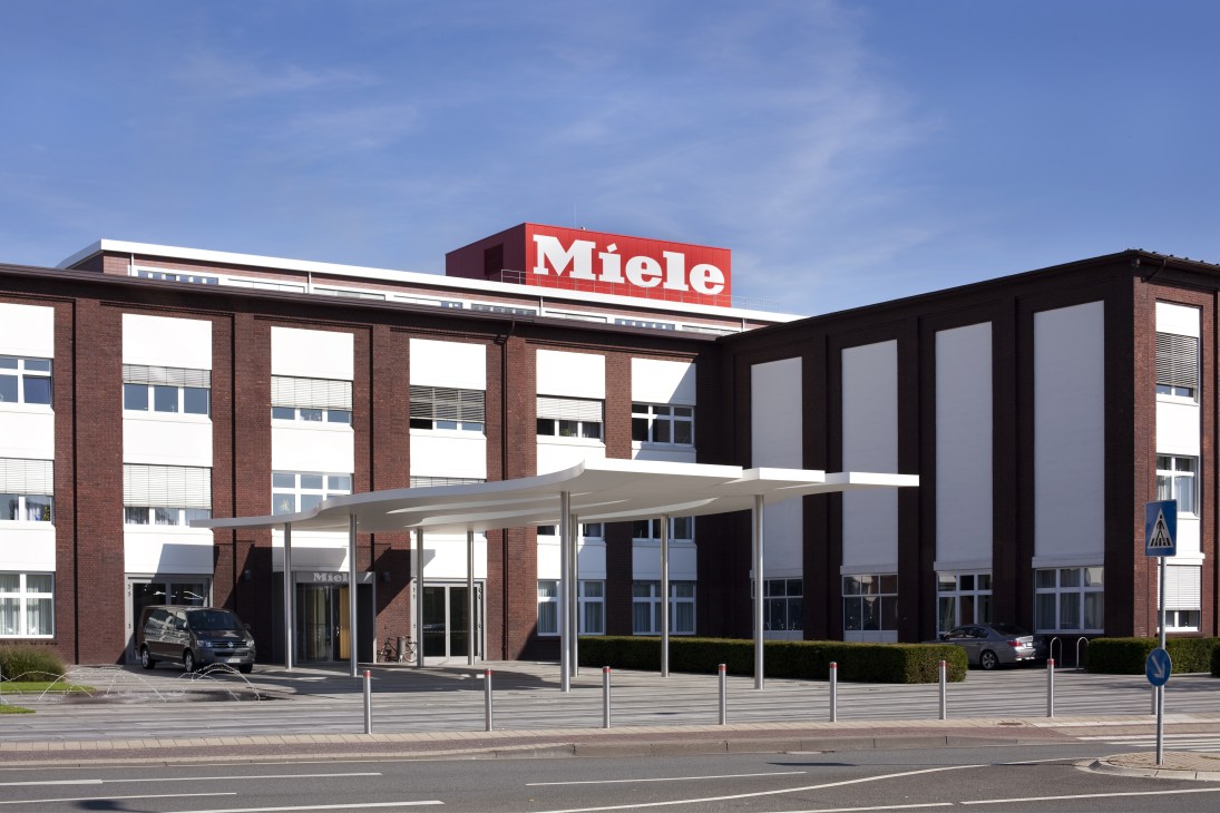 Miele factory building in Gütersloh with red logo sign and modern brick architecture.
