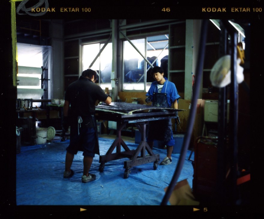 Two workers assemble a car panel at a workbench in the Mitsuoka Motors factory in Toyama.