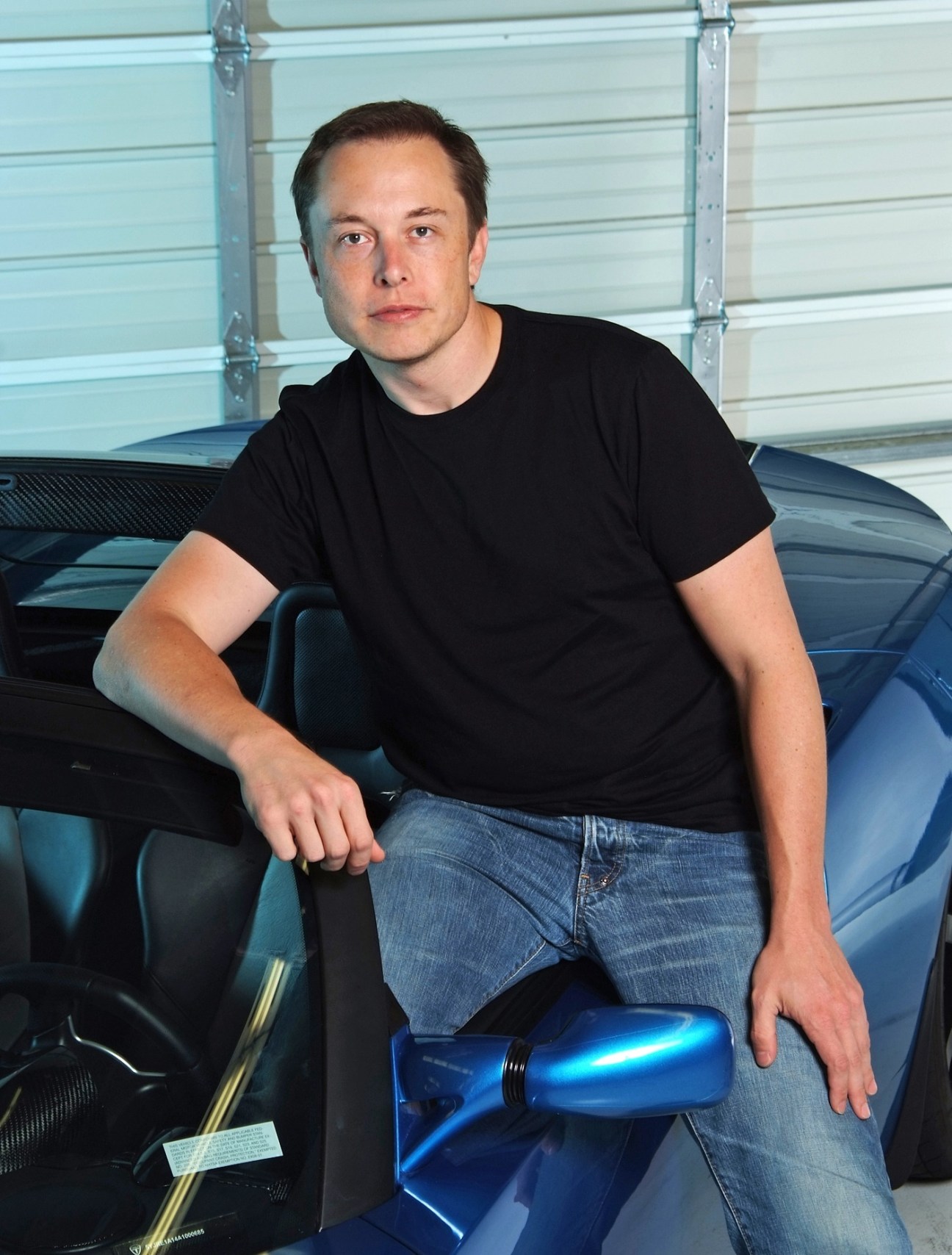 Elon Musk, PayPal co-founder and Tesla Motors CEO, poses next to a Tesla vehicle in a garage.