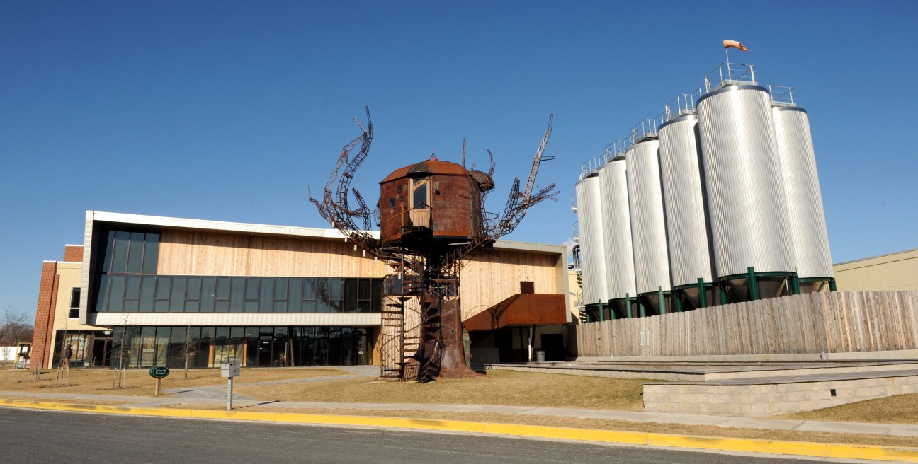 Dogfish Head brewery exterior featuring modern brick building, rustic water tower, and white metal storage tanks.