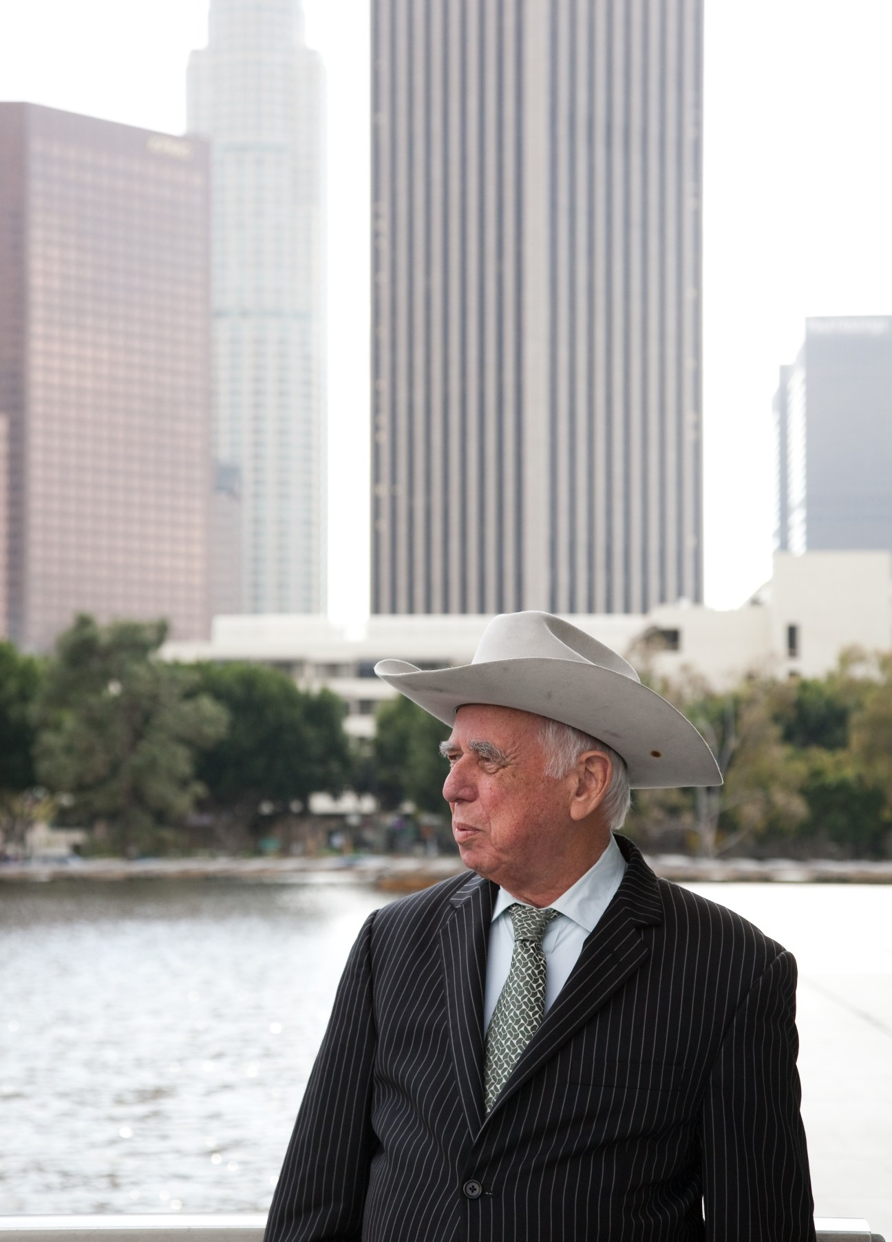 David Freeman, head of the LA Department of Public Works, wearing a cowboy hat and pinstriped suit beside a river with city skyline behind him.