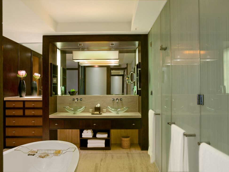 Luxurious hotel bathroom with dual vanity sinks, large mirror, and glass shower enclosure.