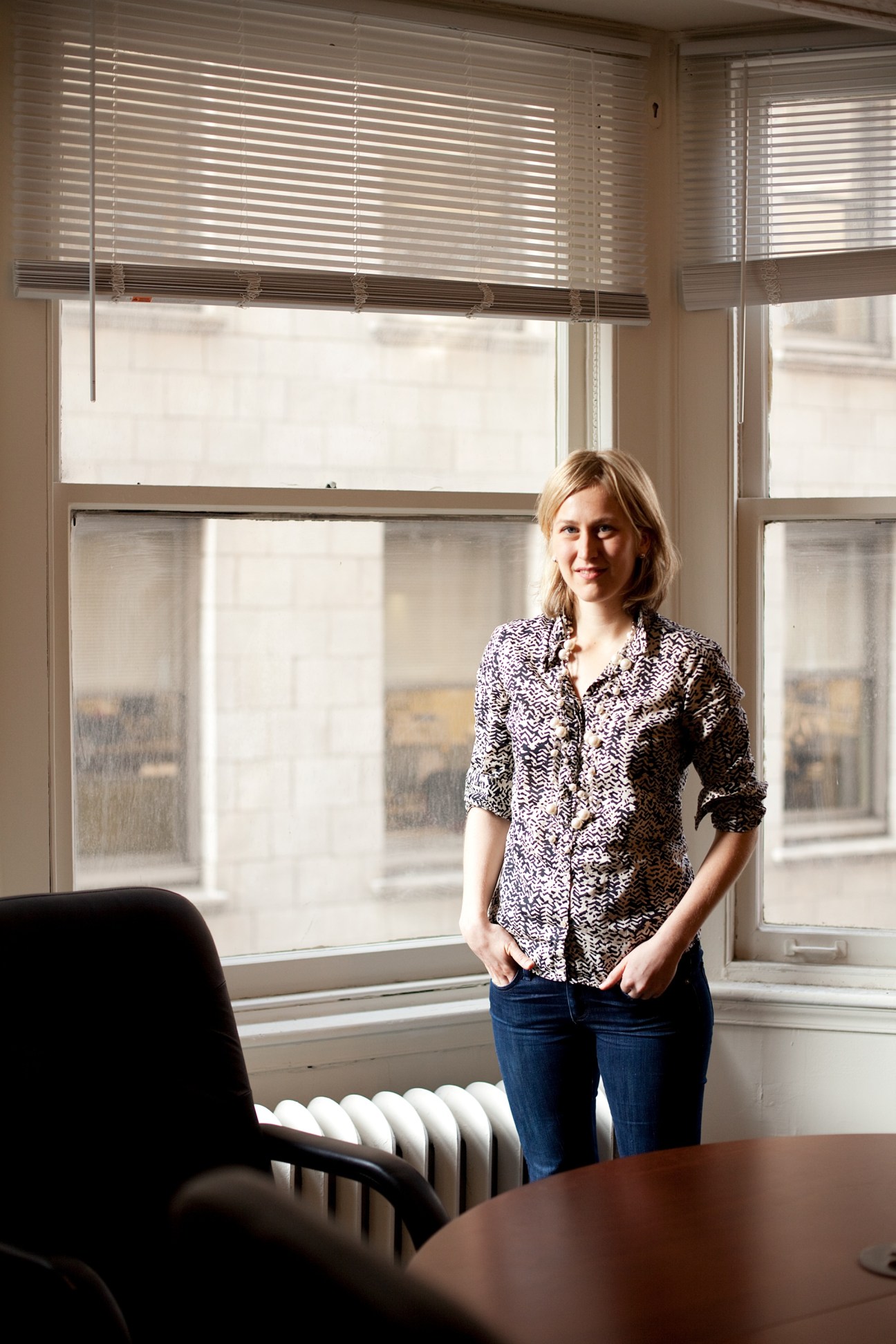 Diana Lind, editor-in-chief of Next American City magazine, standing in an office with large windows.