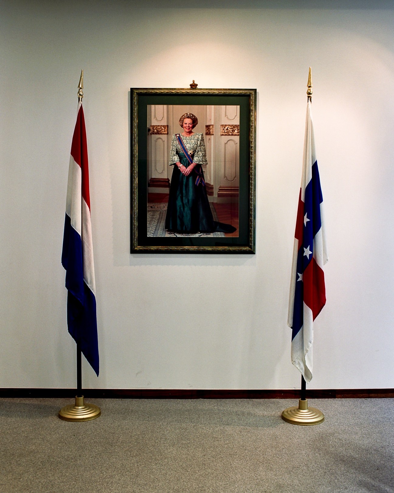 Portrait of Queen Beatrix flanked by Dutch and Antilles flags at Fort Amsterdam.