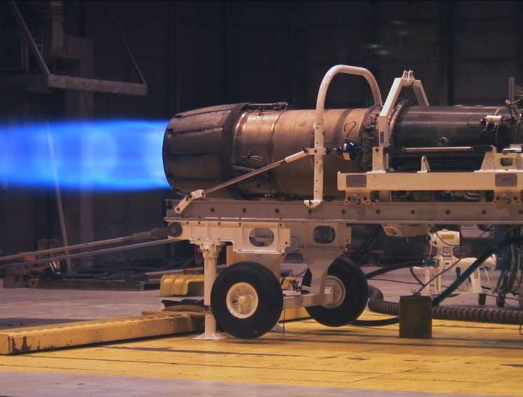 F/A-18 aircraft engine being tested to run on biofuel, emitting bright blue flame during test.