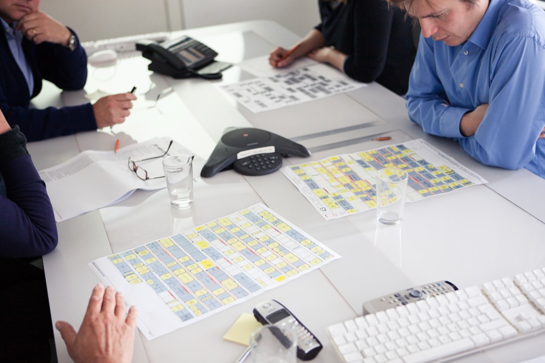 Photo editors review and plan weekly picture selections at a conference table with printed layouts.
