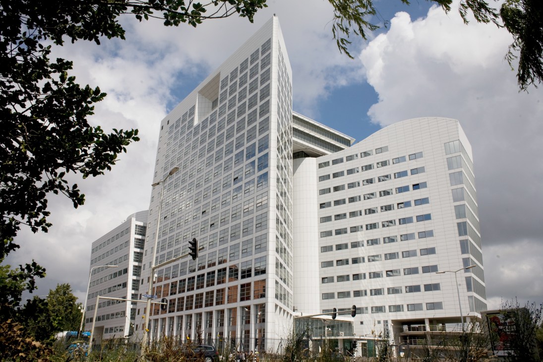 Modern white building complex of the International Criminal Court in The Hague, surrounded by trees.
