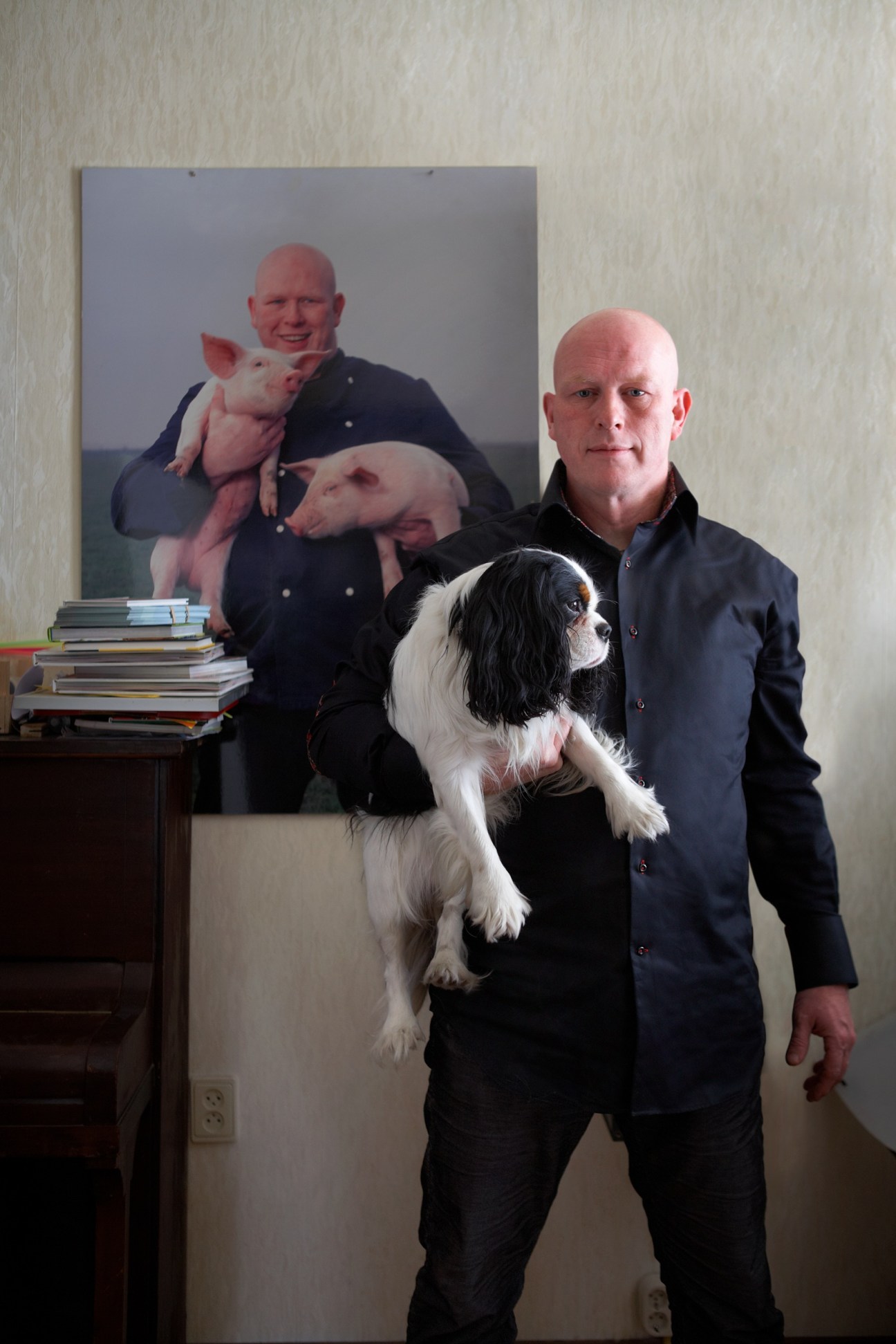Chef Pierre Wind holds his black and white dog Mr Teun in front of a portrait photograph.