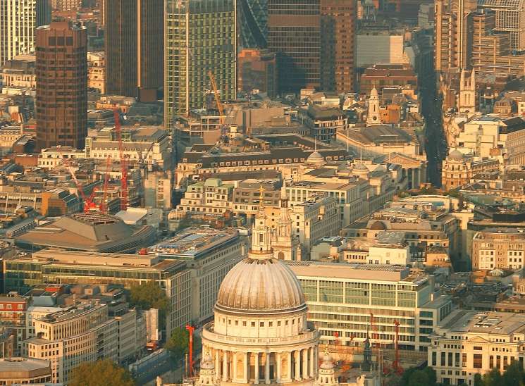Aerial view of London's St Paul's Cathedral and surrounding cityscape at sunset.